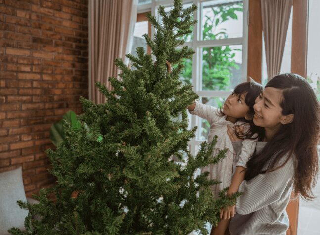 a mom and daughter setting up a christmas tree
